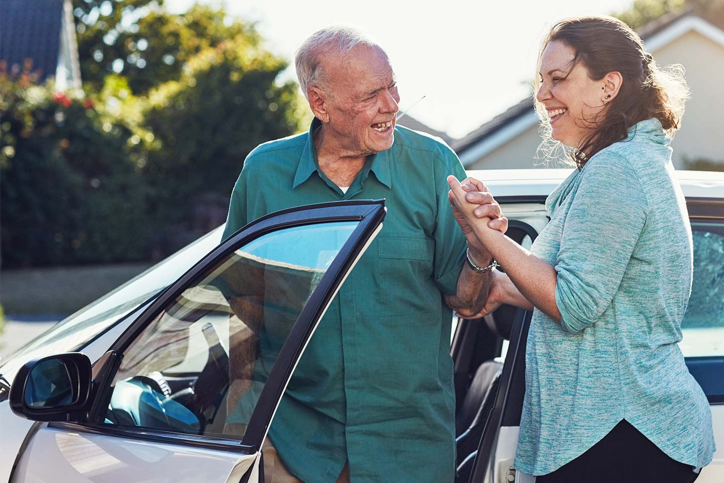 Photo of man and woman wearing green next to a car
