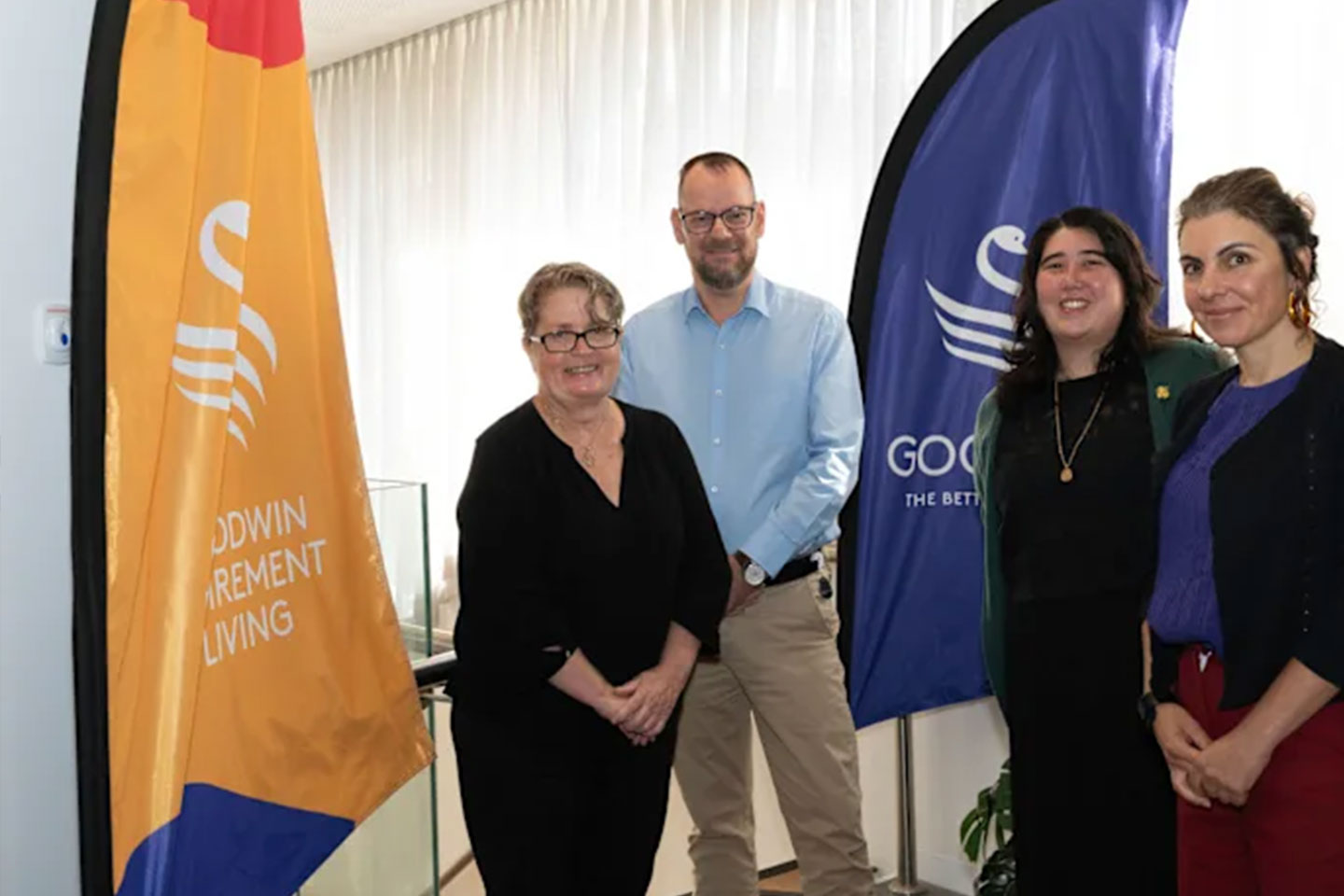 Photo of four smiling people standing next to banners
