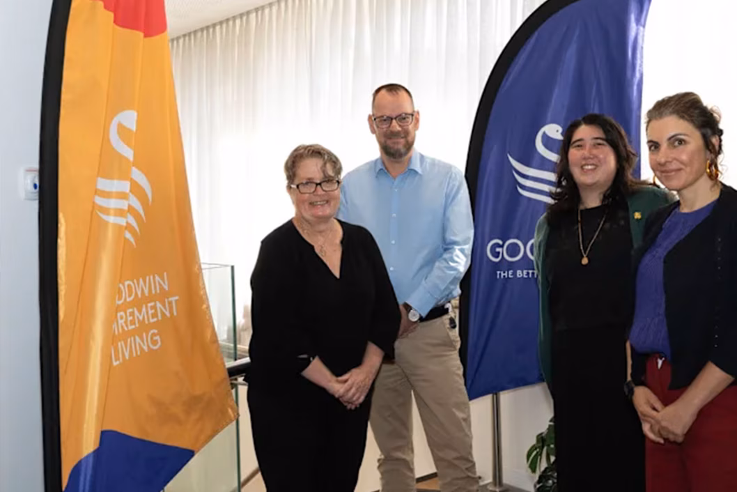 Photo of four smiling people standing next to banners