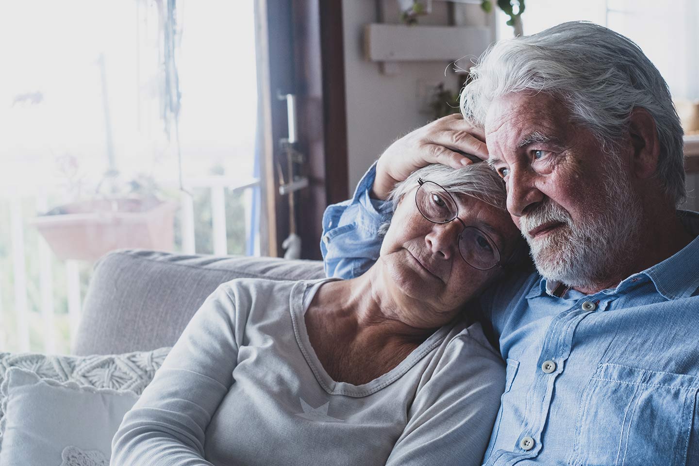 Photo of older couple sitting in each others arms on a white sofa