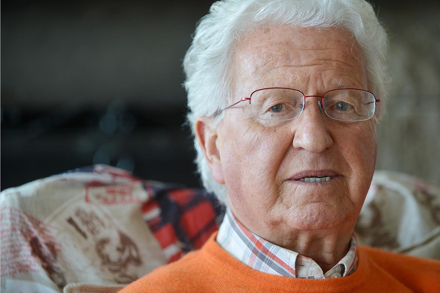 Photo of a man wearing glasses and an orange jumper