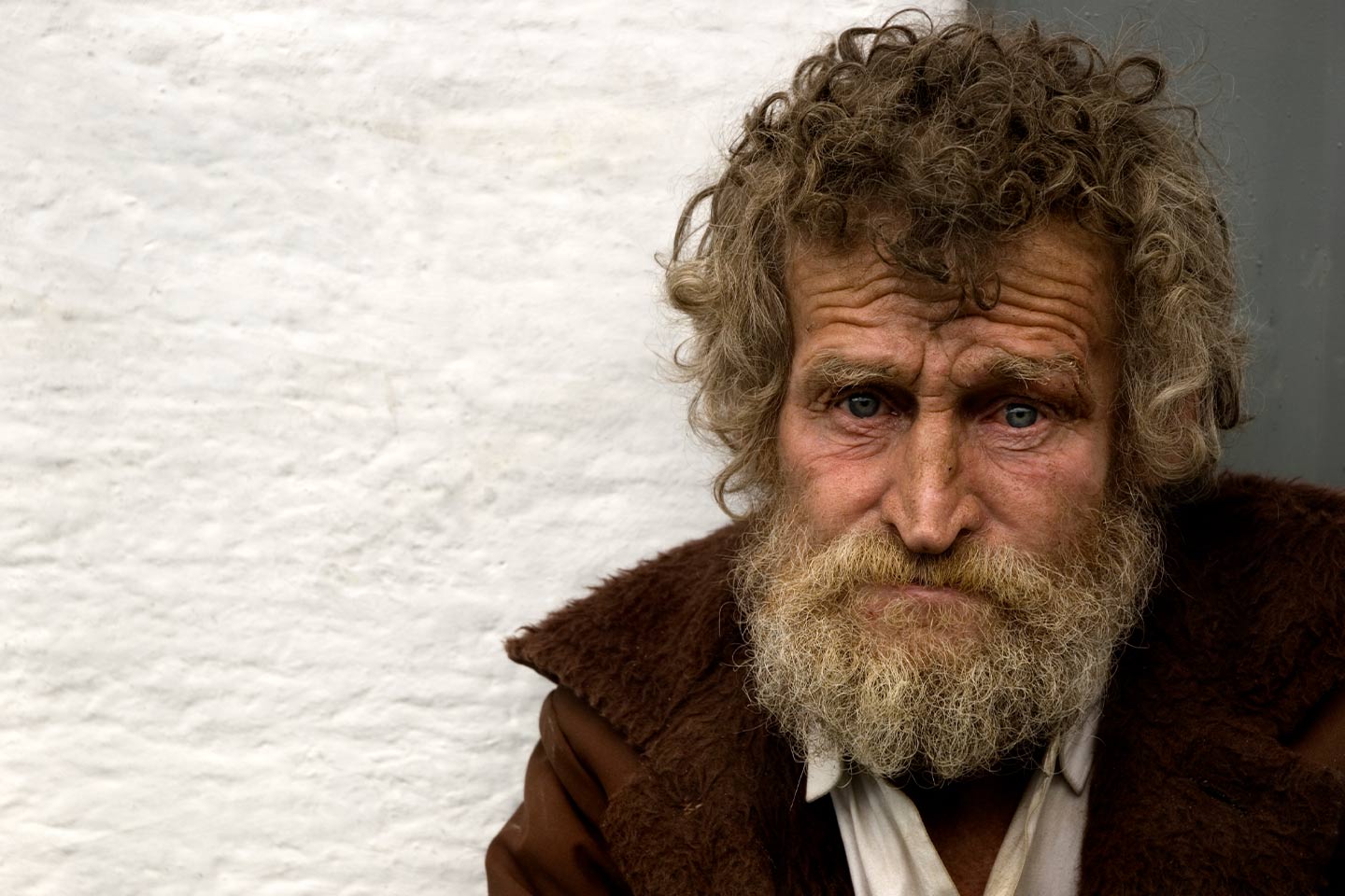 Photo of a man with curly brown hair and a brown jacket
