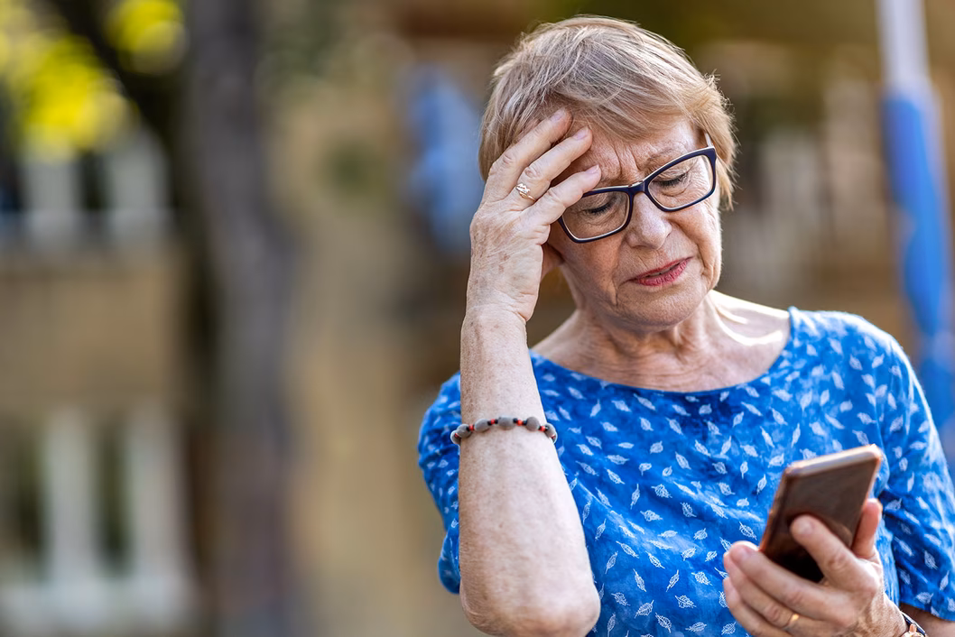 Photo of a woman in blue top looking at her mobile phone