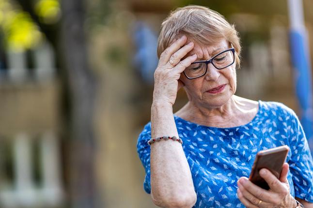 Photo of a woman in blue top looking at her mobile phone