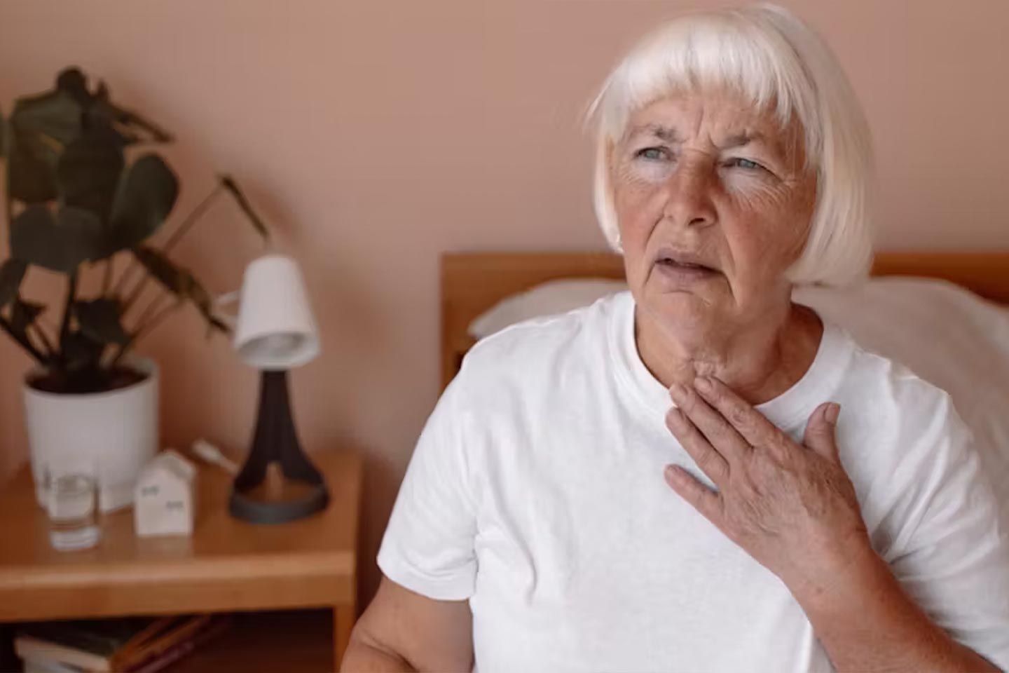 Photo of a woman touching her throat with her fingertips