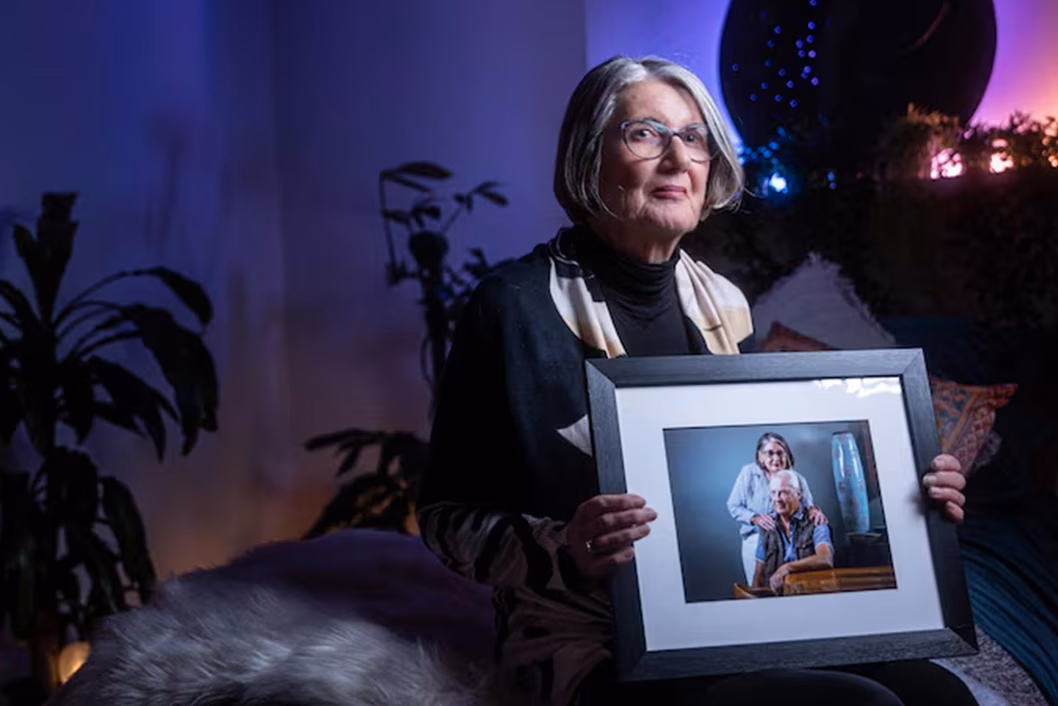 Photo of a woman in a darkened room holding a framed portrait