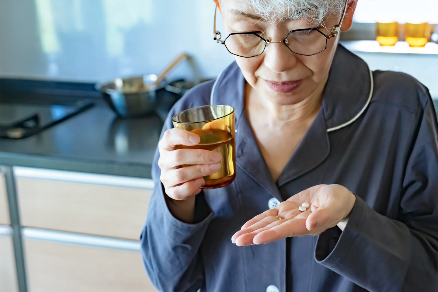 Photo of a woman with a glass of water holding two tablets