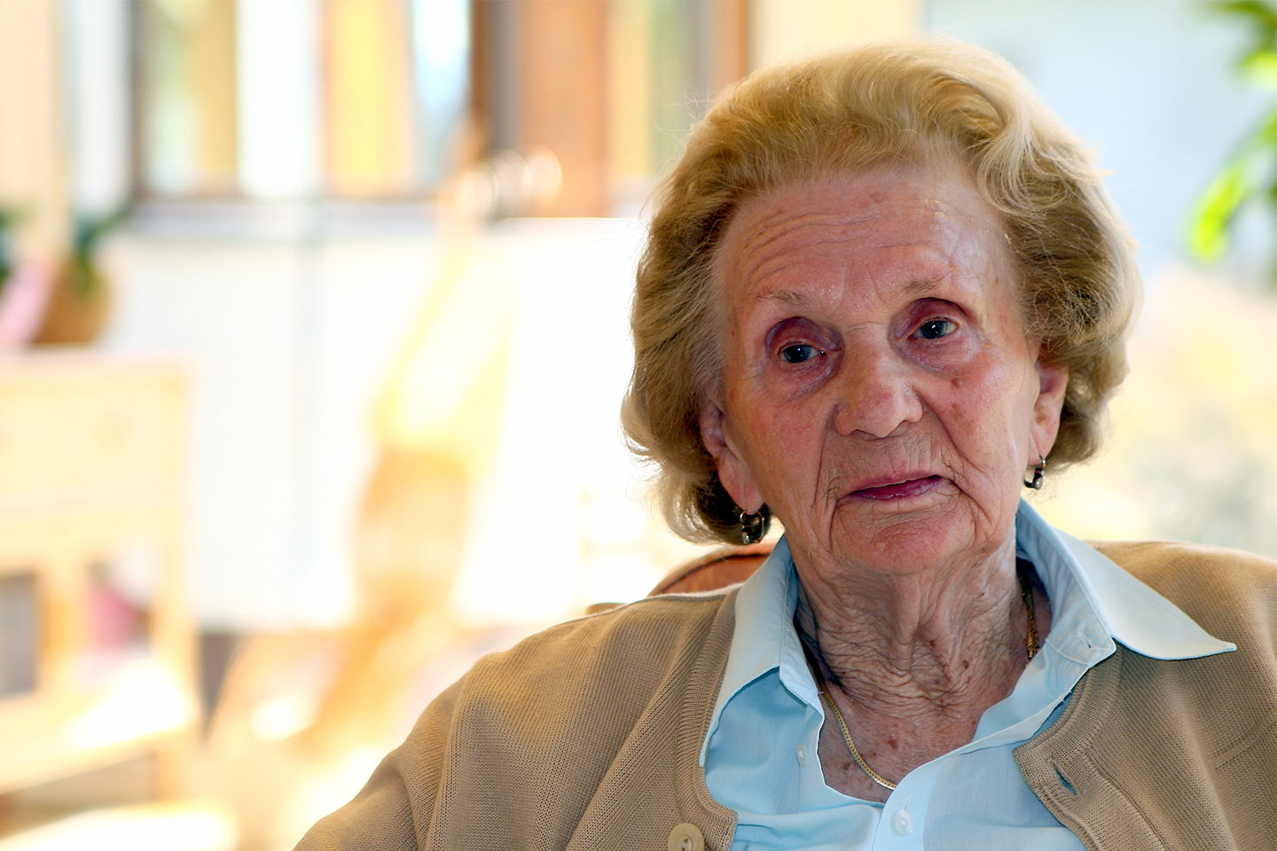 Photo of a sad woman in a pale blue shirt and beige cardigan