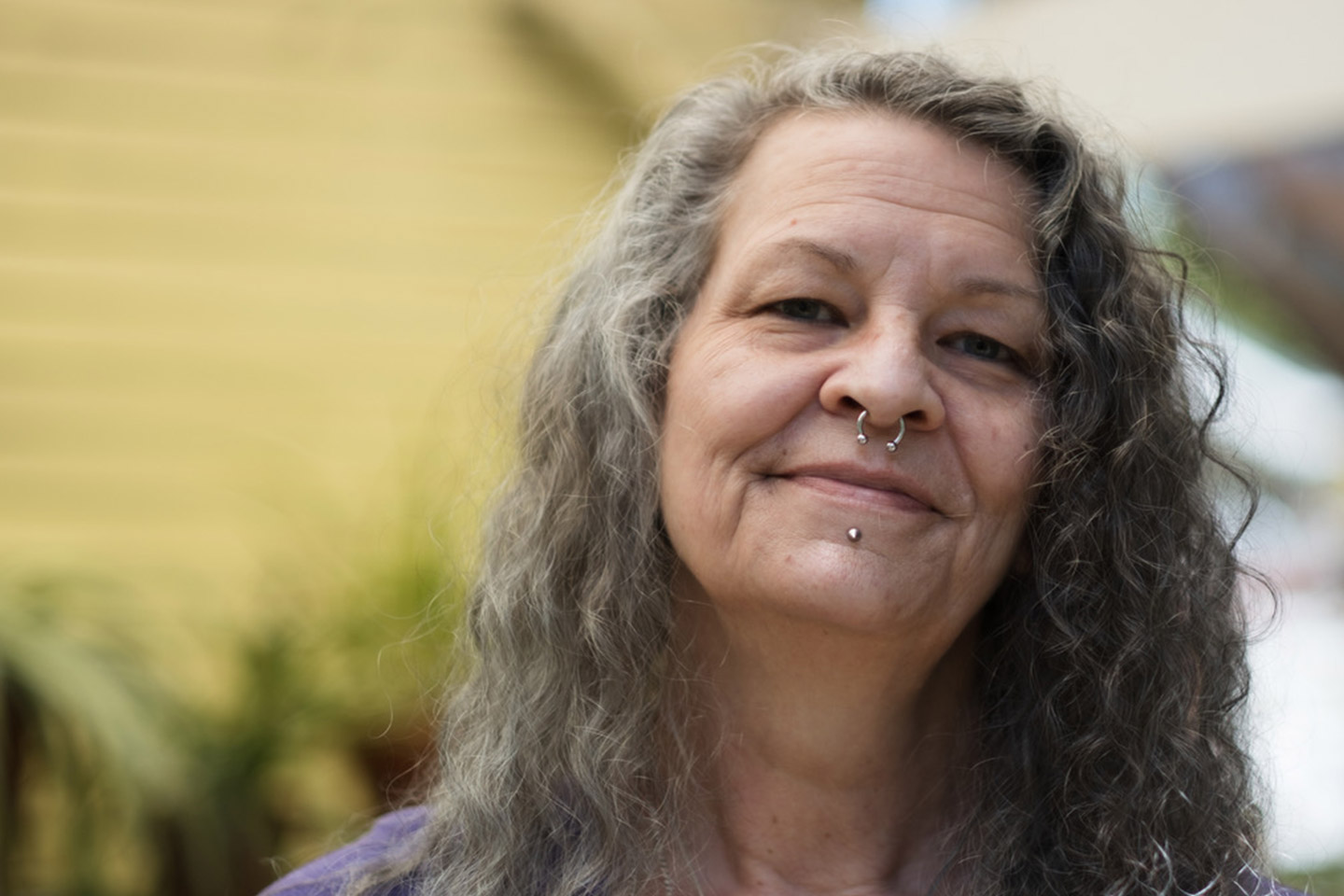 Image of an older woman with long grey hair and a nose piercing.