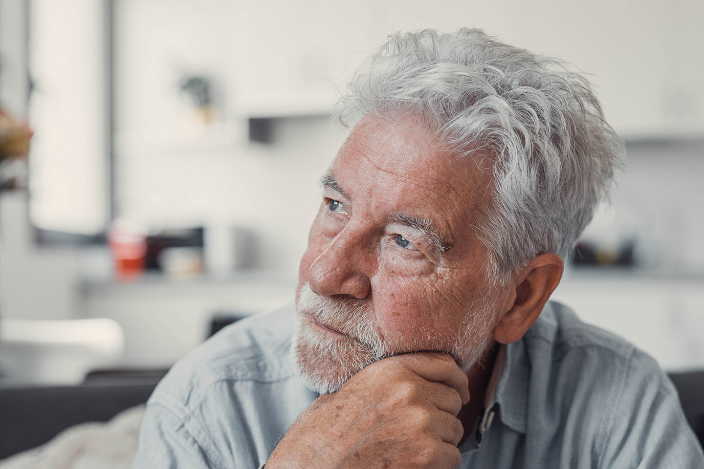 Photo of a man with silver hair and beard resting his chin on his hand