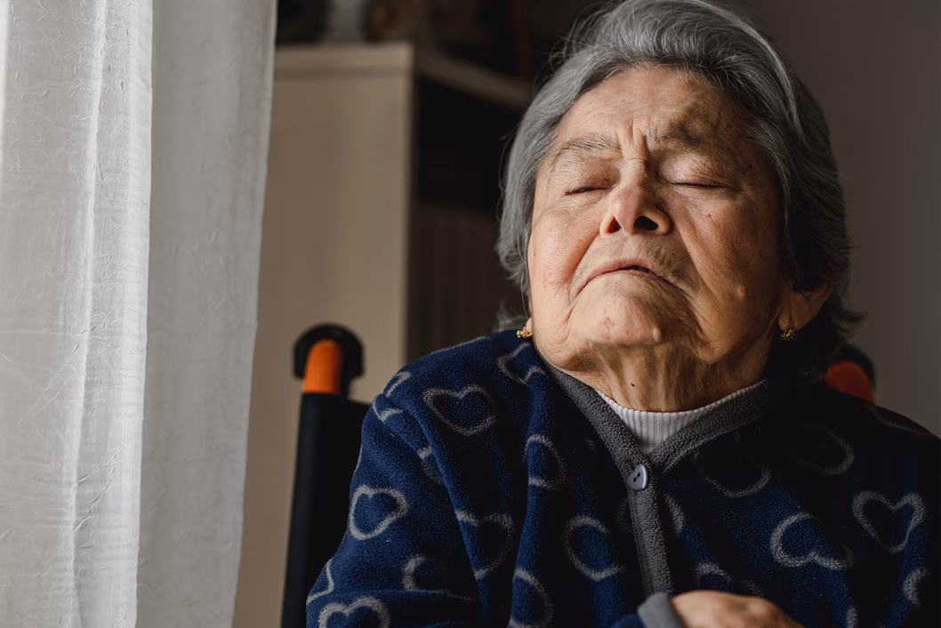 Photo of an elderly woman asleep in her wheelcahiar