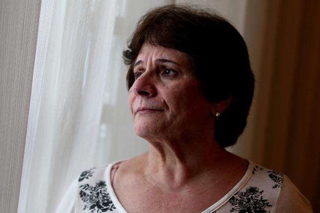Image of an older woman with dark hair looking out of a window