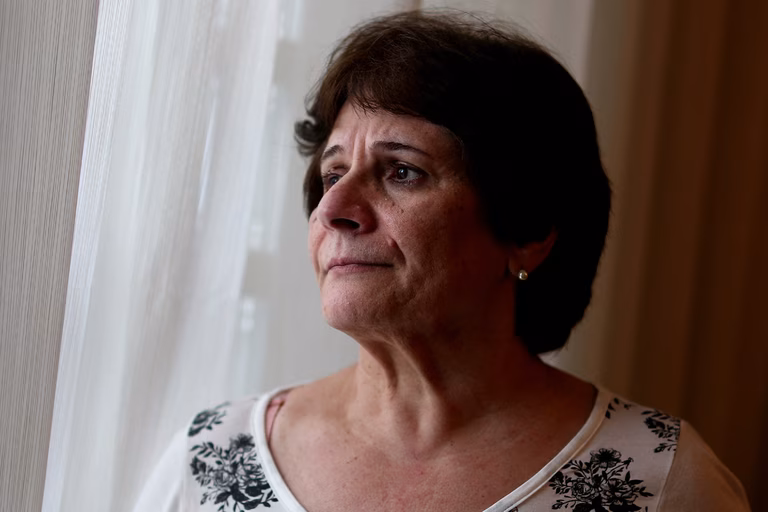 Image of an older woman with dark hair looking out of a window