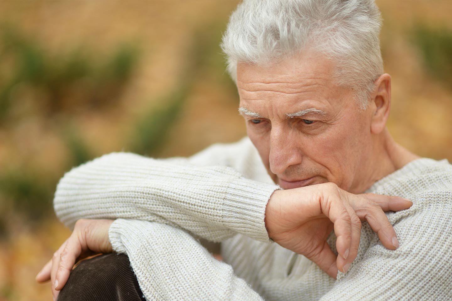 Photo of a man in a cream jumper looking pensive