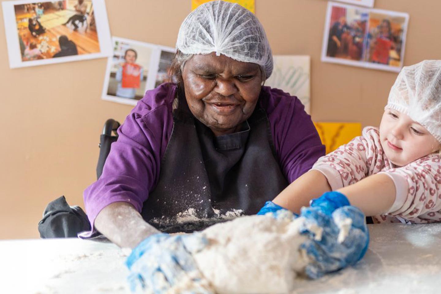 Photo of woman in an apron and a child kneading dough together