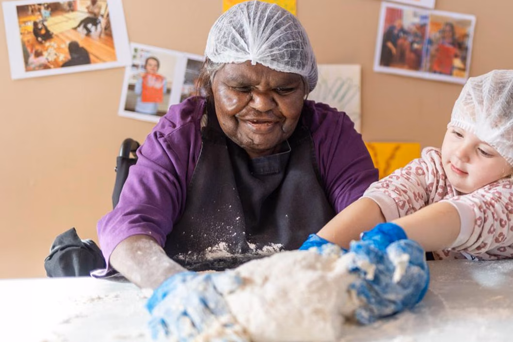 Photo of woman in an apron and a child kneading dough together
