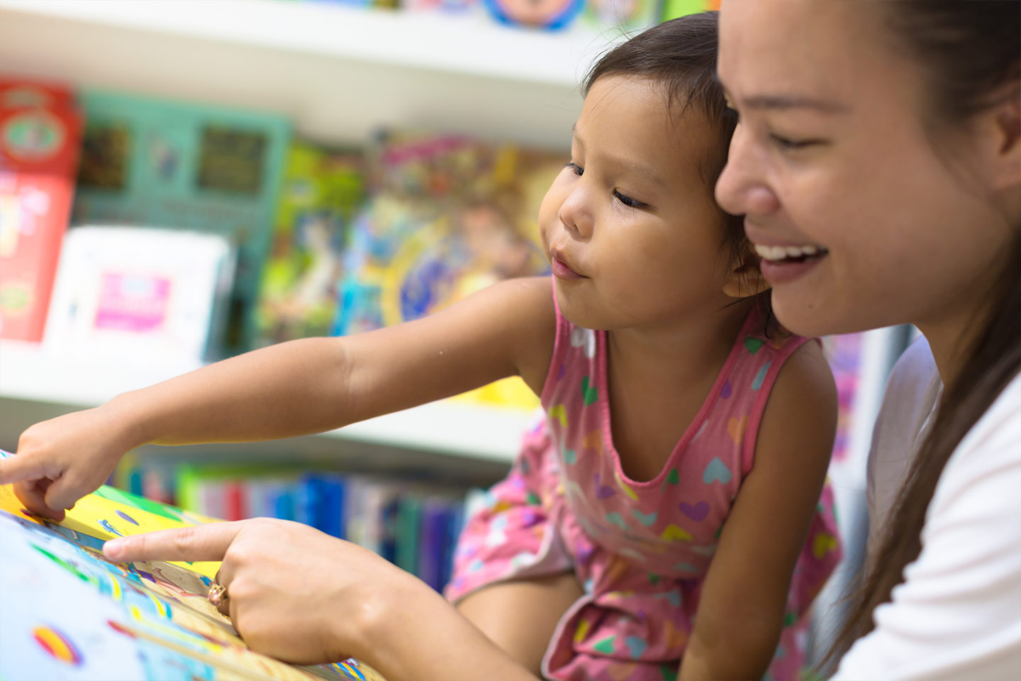 Photo of a young child and woman pointing to an open book