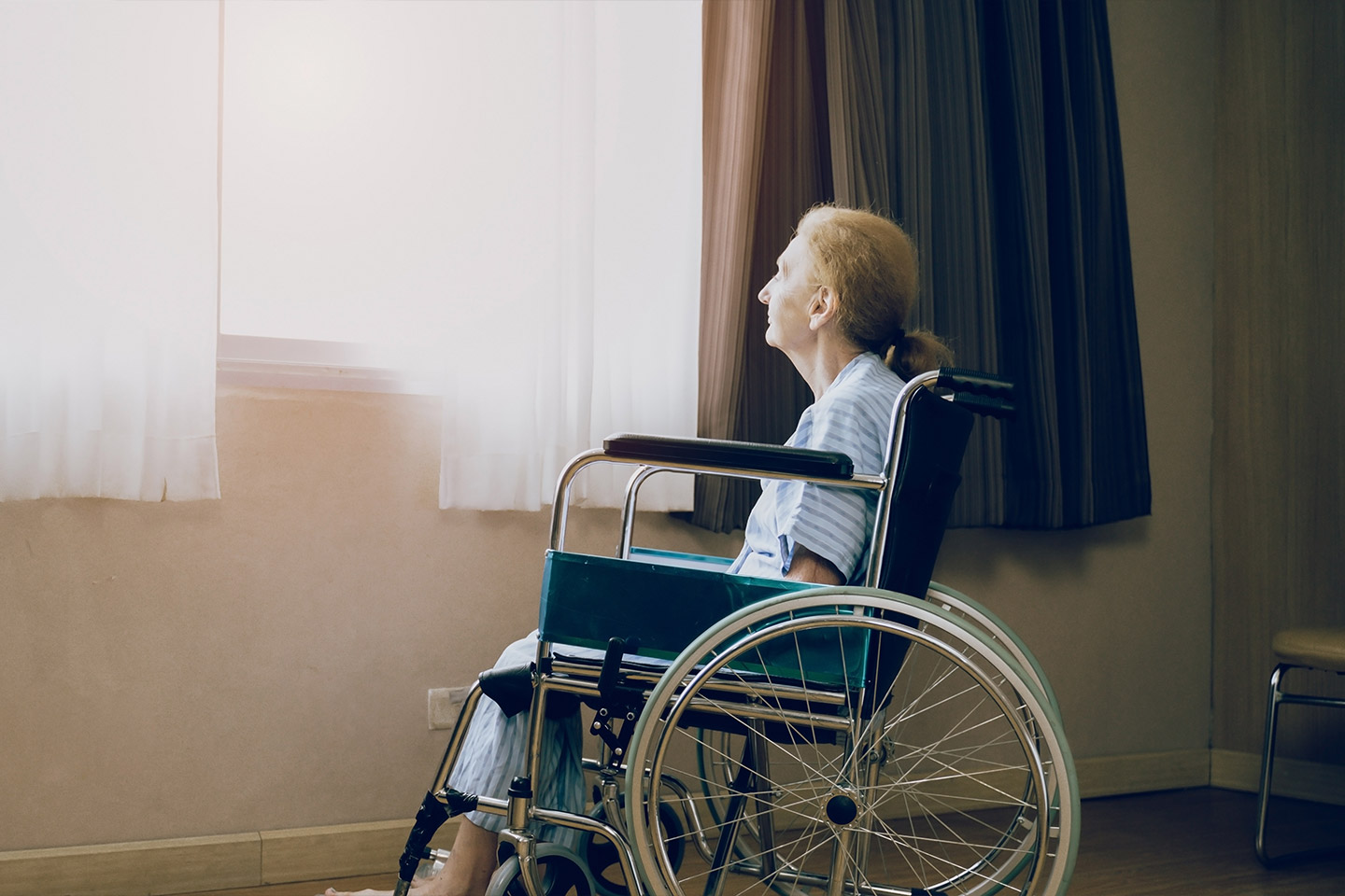 Photo of a person in a wheelchair alone by a window