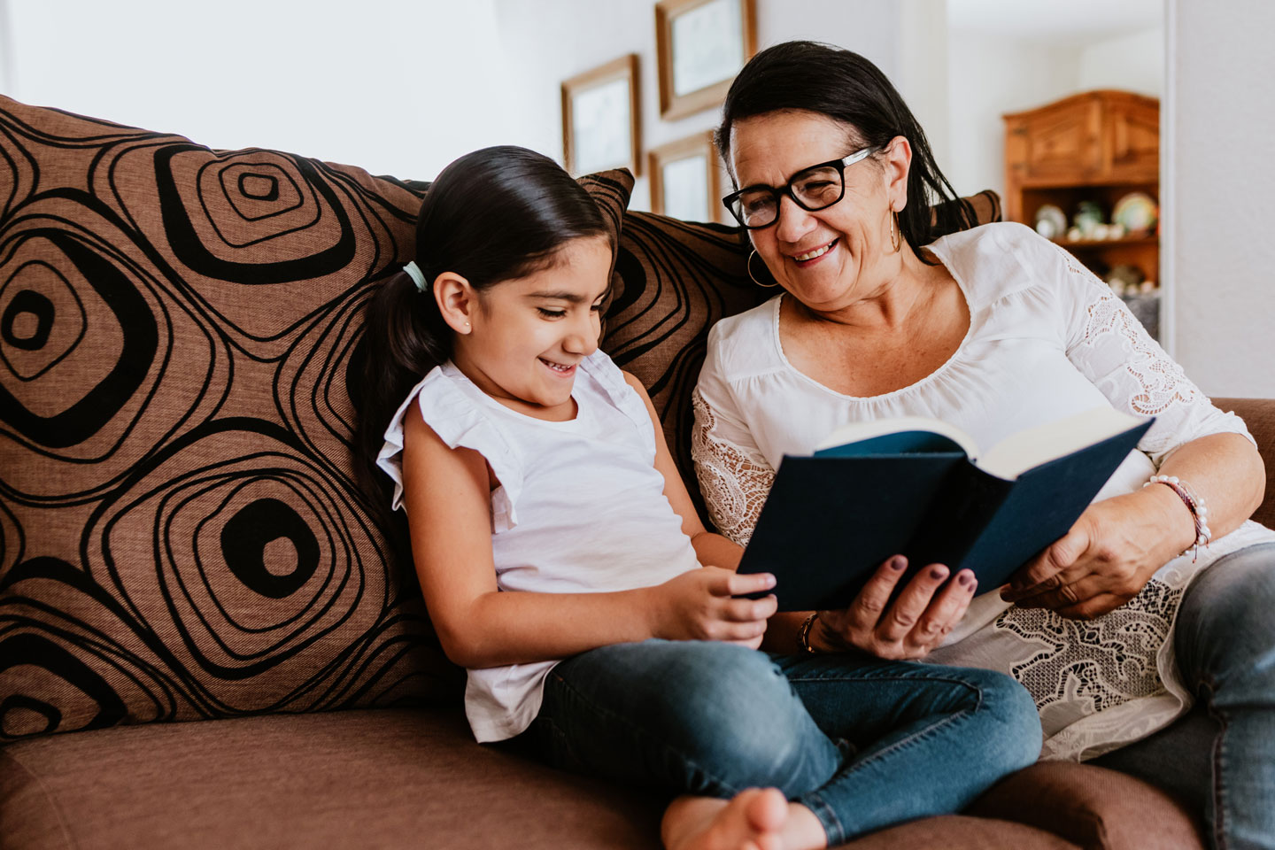 Grandmother and granddaughter reading on the couch.