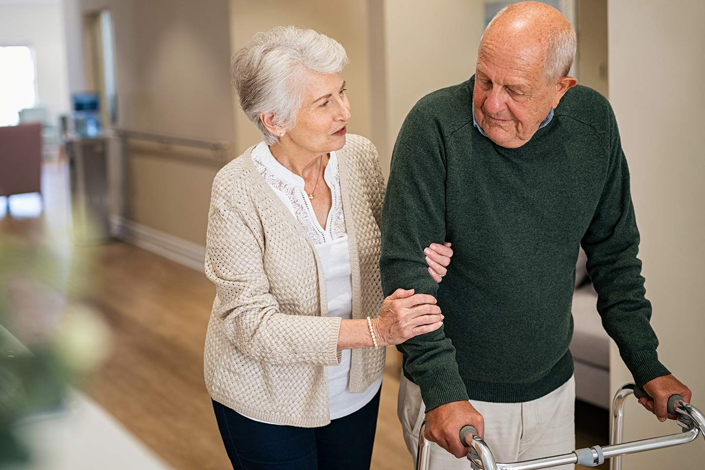 Photo of woman holding the arm of a man using a walker