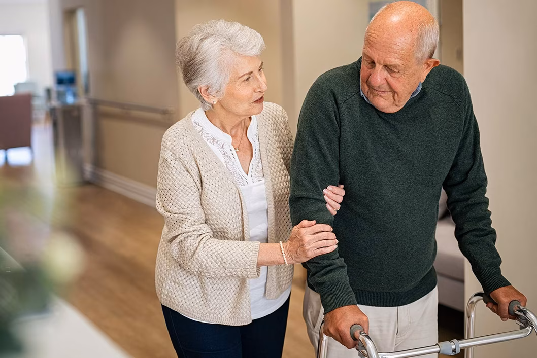 Photo of woman holding the arm of a man using a walker