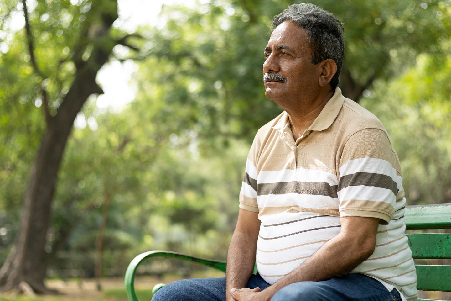Photo of a man in a striped polo sitting on a park bench