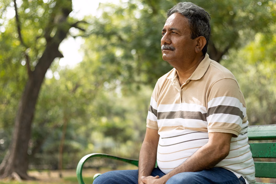 Photo of a man in a striped polo sitting on a park bench