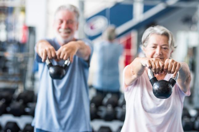 Image of an older woman and an older man exercising with small kettle bells