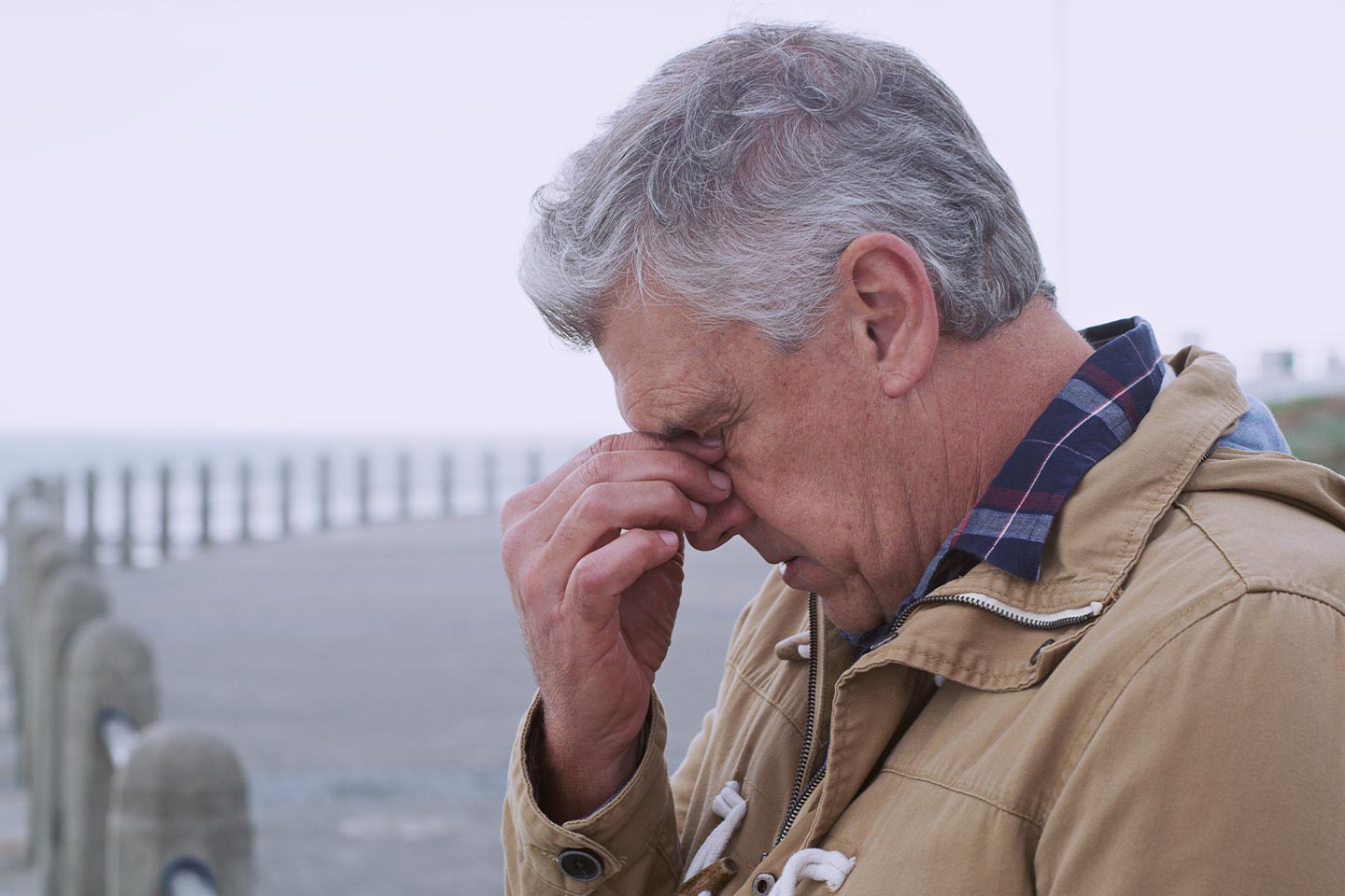 Photo of man at a beach pinching the bridge of his nose