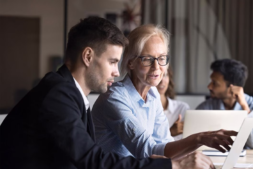 Image of younger and older coworkers both looking at a screen