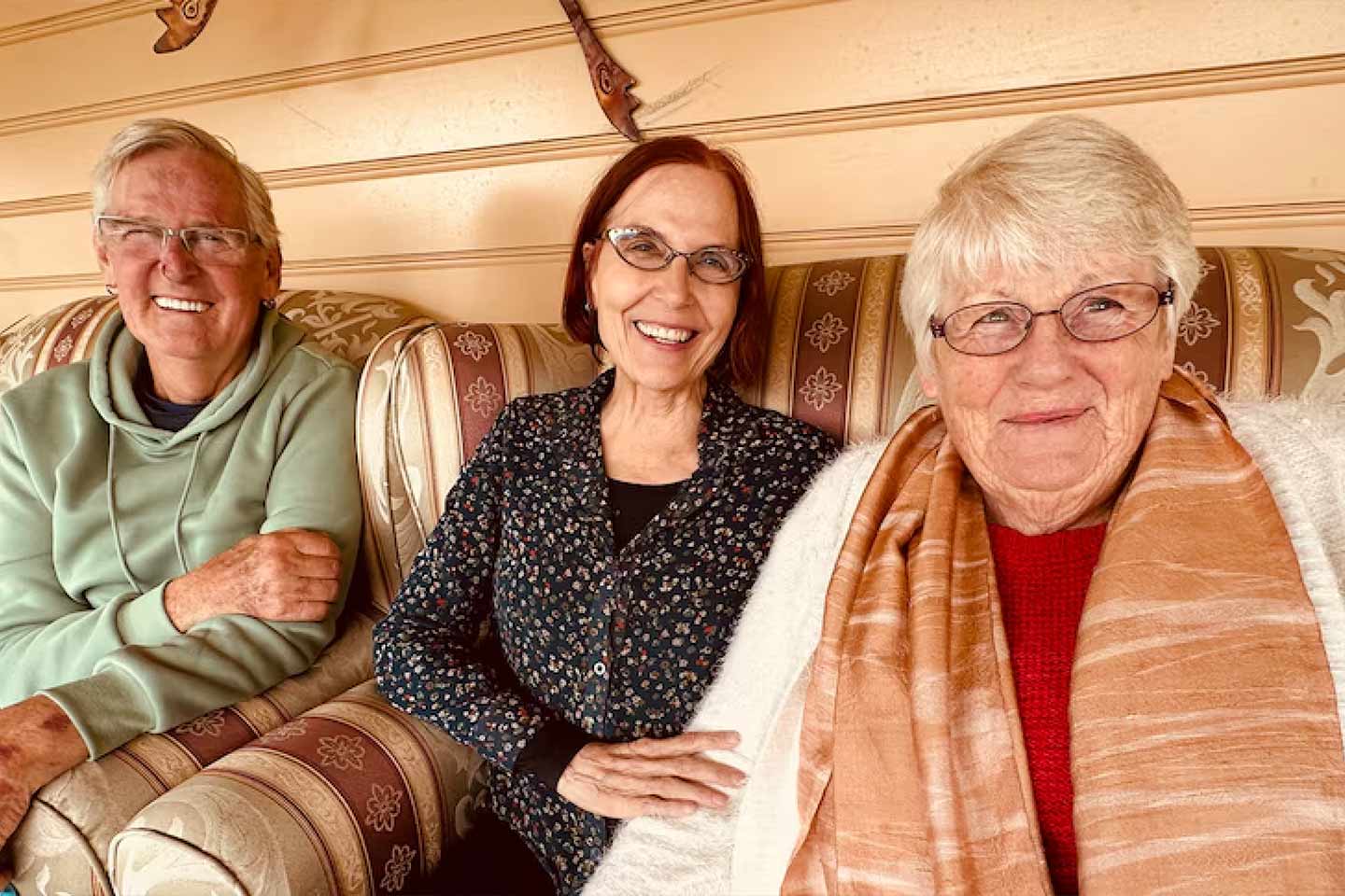 Photo of a man and two women sitting on a couch