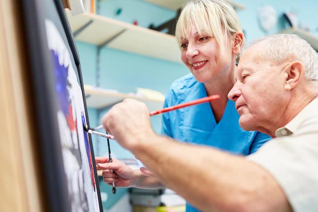 Photo of a man painting while a woman watches