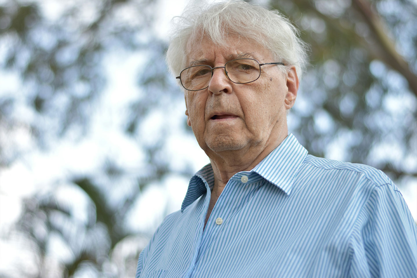 Photo of man wearing glasses and a blue striped shirt