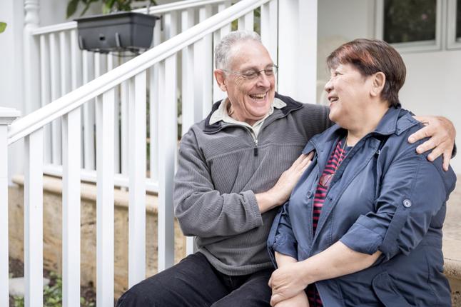 Photo of a man and a woman sitting on a verandah and laughing