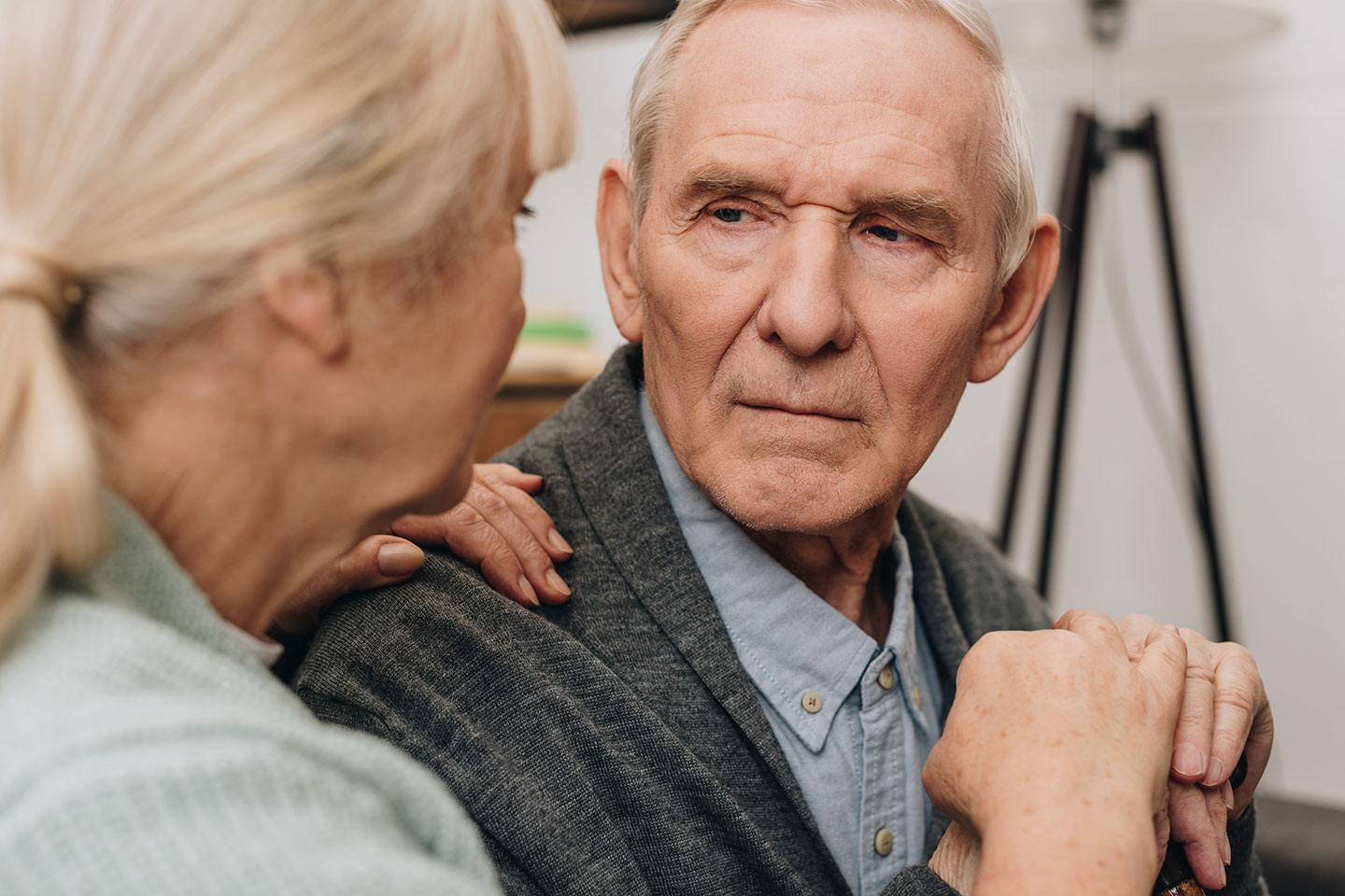 Photo of a woman with a blonde ponytail and her hand on a man's shoulder