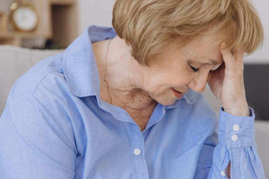 Photo of a woman in a blue blouse with her head in her hand