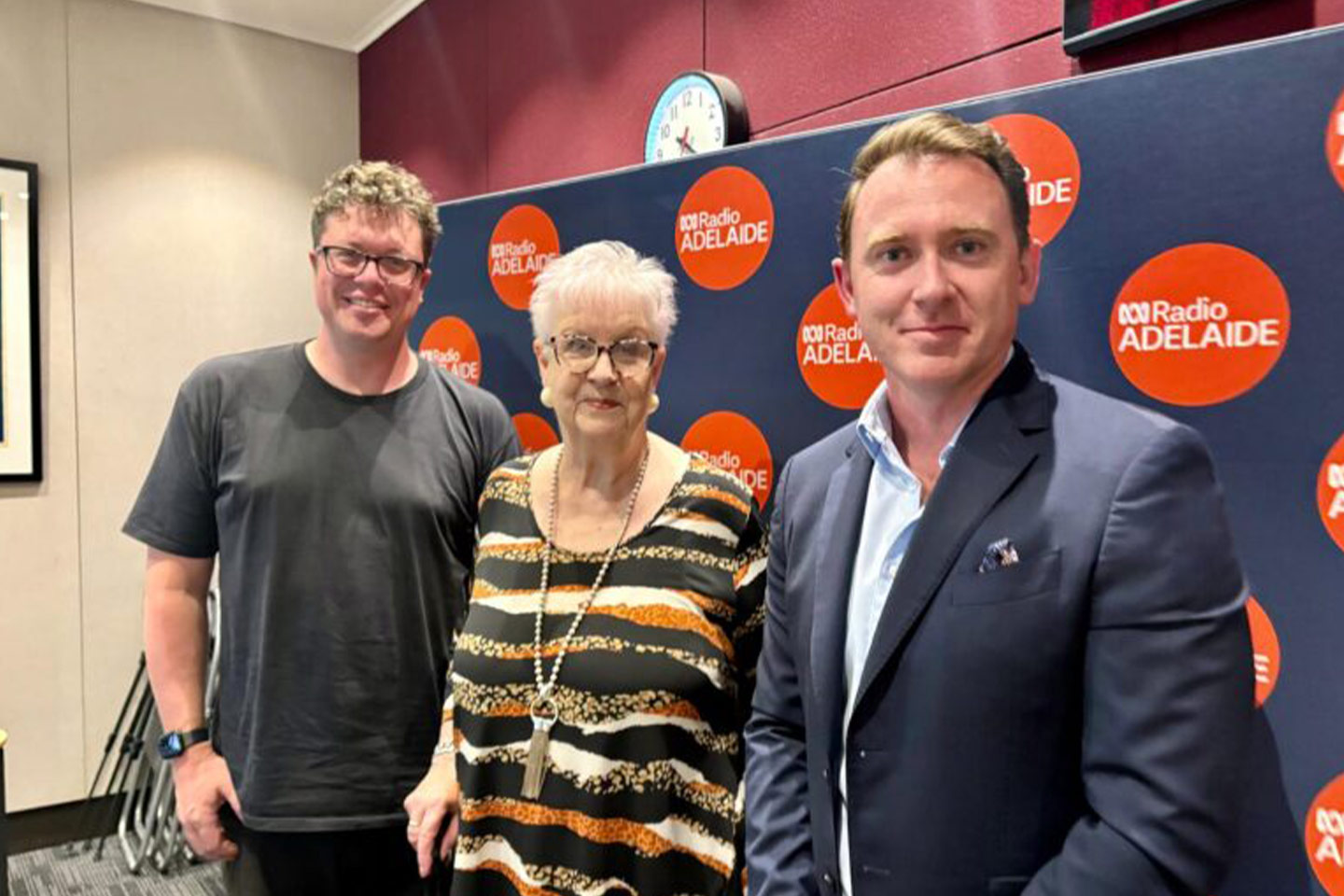 Photo of three people standing in front of an ABC Radio banner