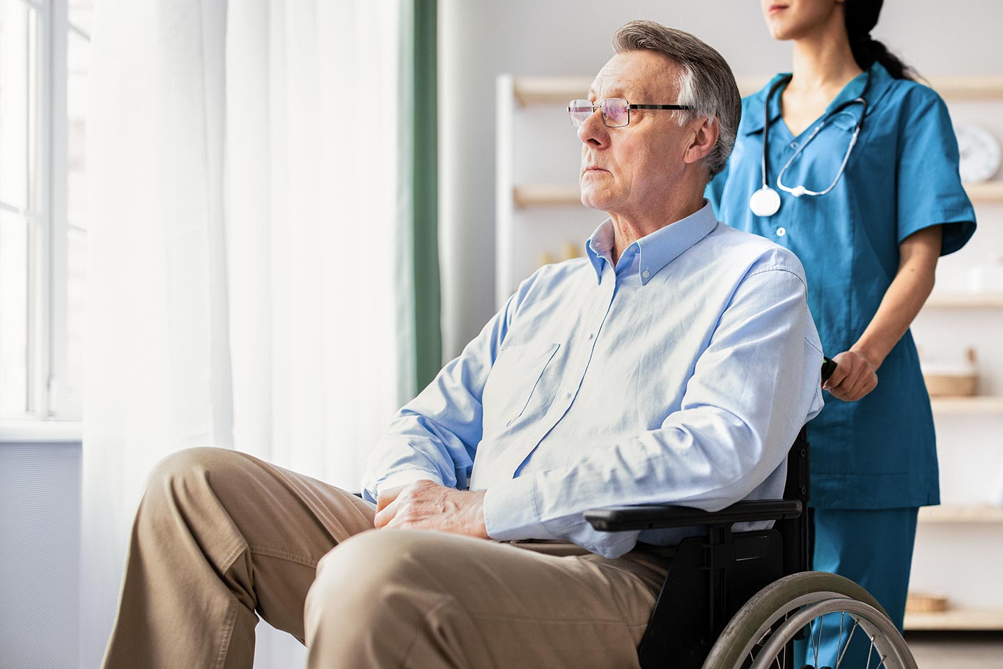 Photo of a man being wheeled by a health worker