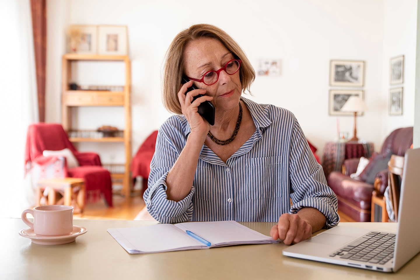 Photo of woman in a home office using a mobile phone
