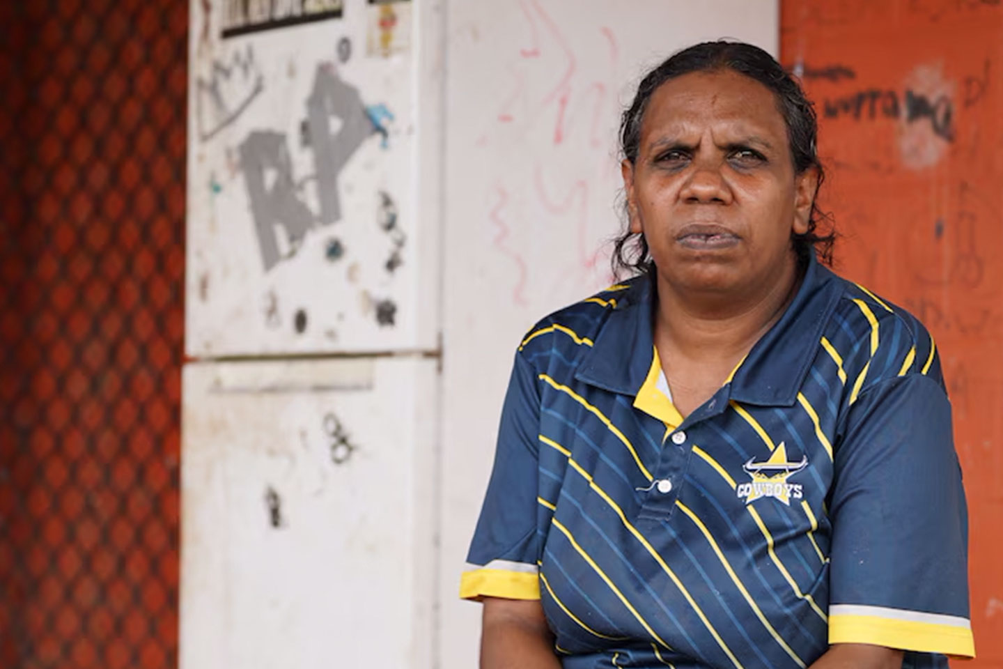 Photo of a woman wearing a polo shirt in front of an old fridge