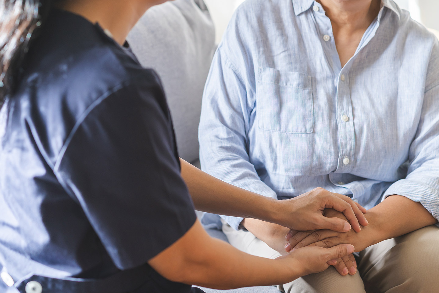 Photo of a helper holding the hands of a woman in a pale blue shirt