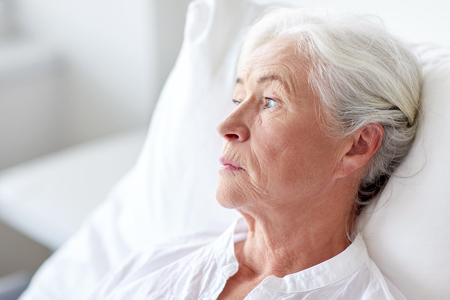 Photo of a women in white lying on a white pillow