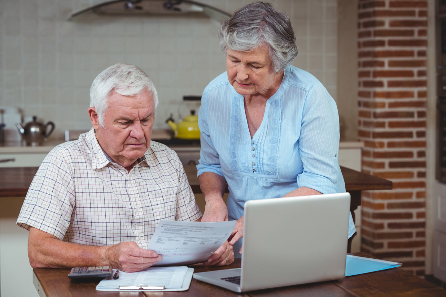 Picture of an older man and woman at a kitchen table reviewing documents