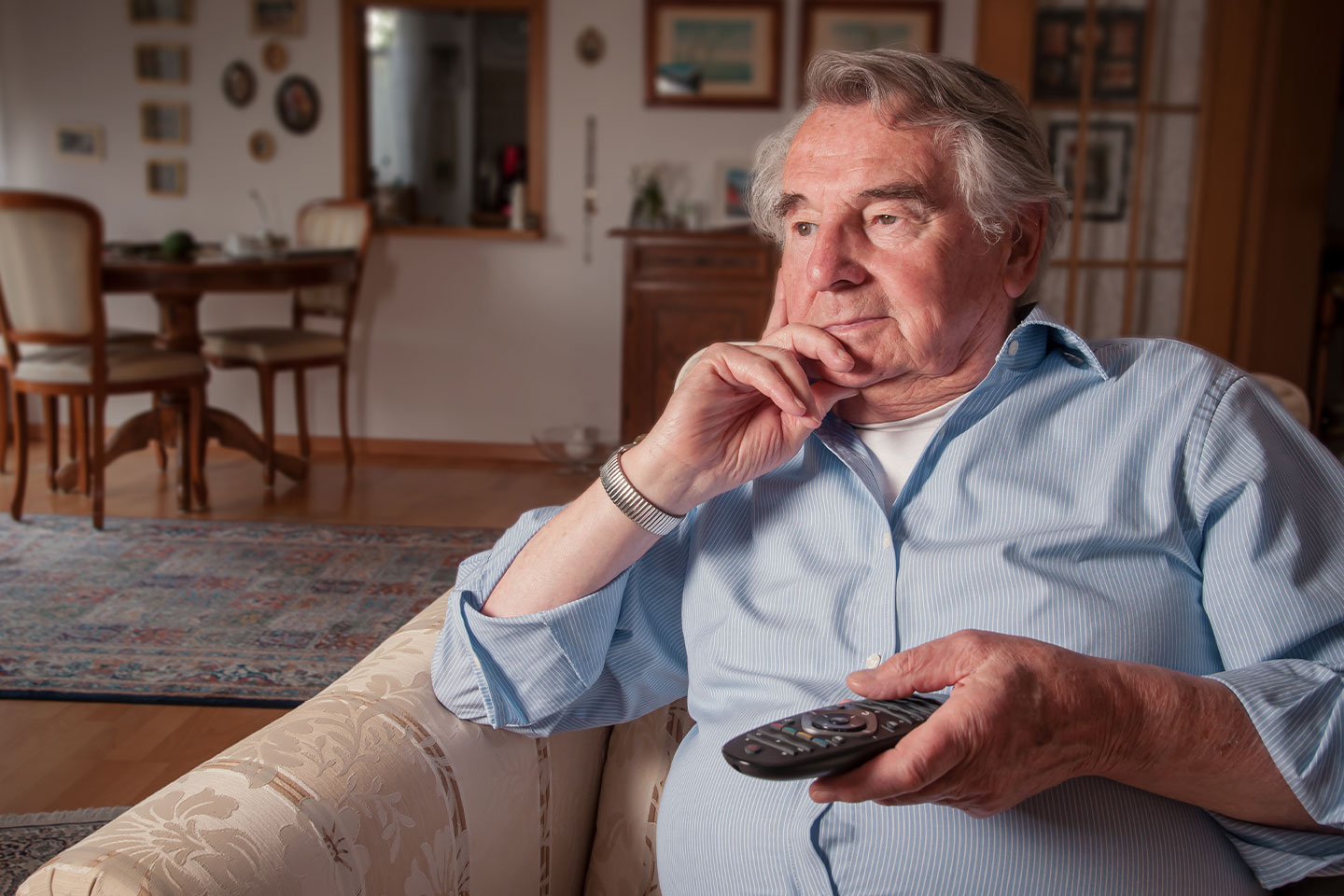 Photo of a man in a blue shirt holding a TV remote control