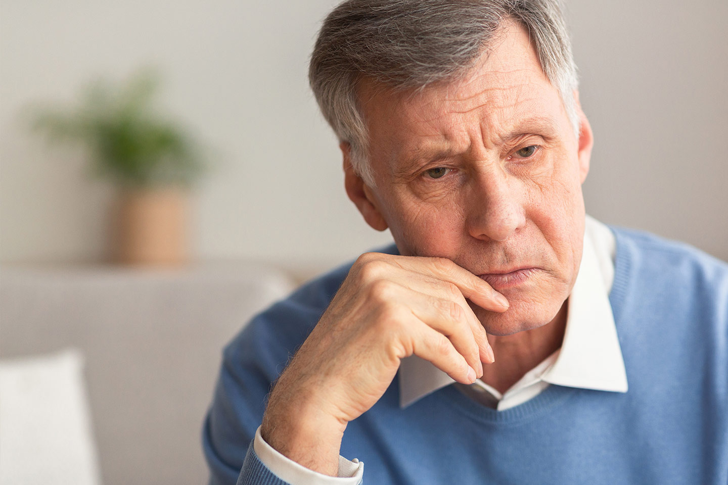 Photo of a man in a blue jumper and white shirt looking pensive