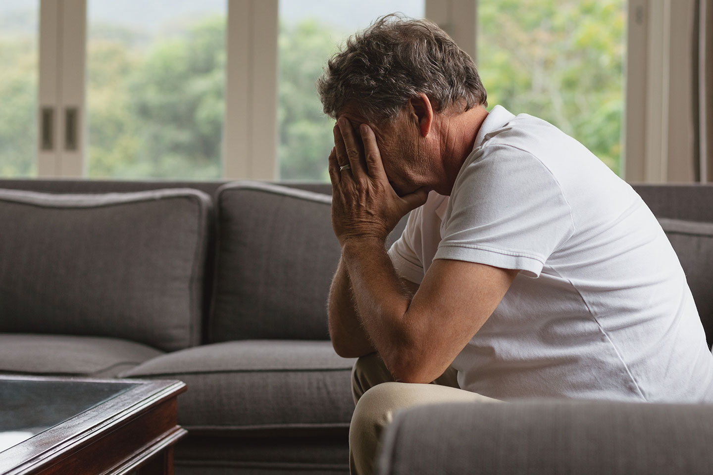 Photo of a man sitting on a couch with head in hands