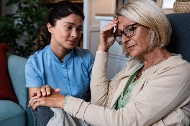 Photo of woman with glasses being comforted by a helper