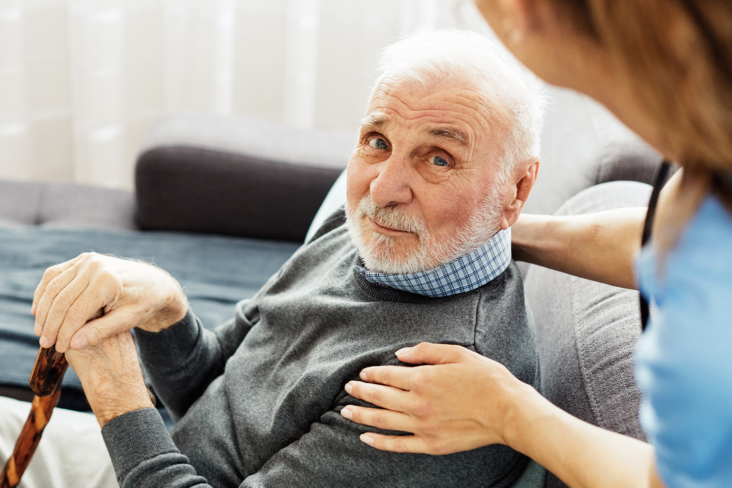 Photo of a man with a walking stick and a health worker