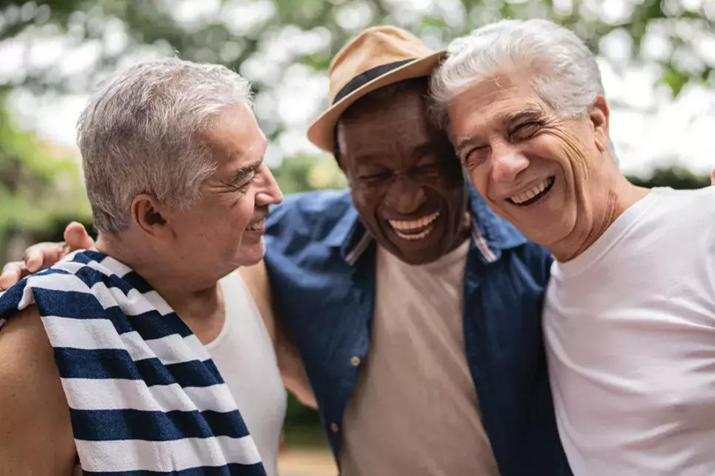 Photo of three men embracing and laughing together
