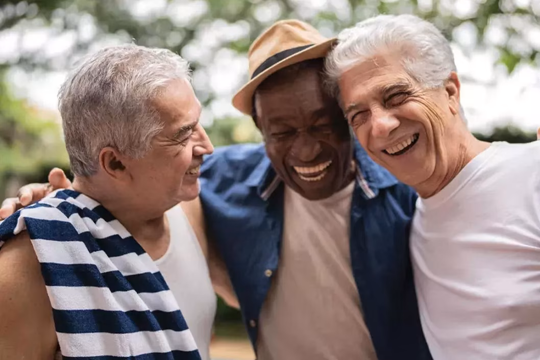 Photo of three men embracing and laughing together